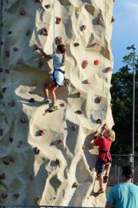 Children climbing a tall artificial rock wall