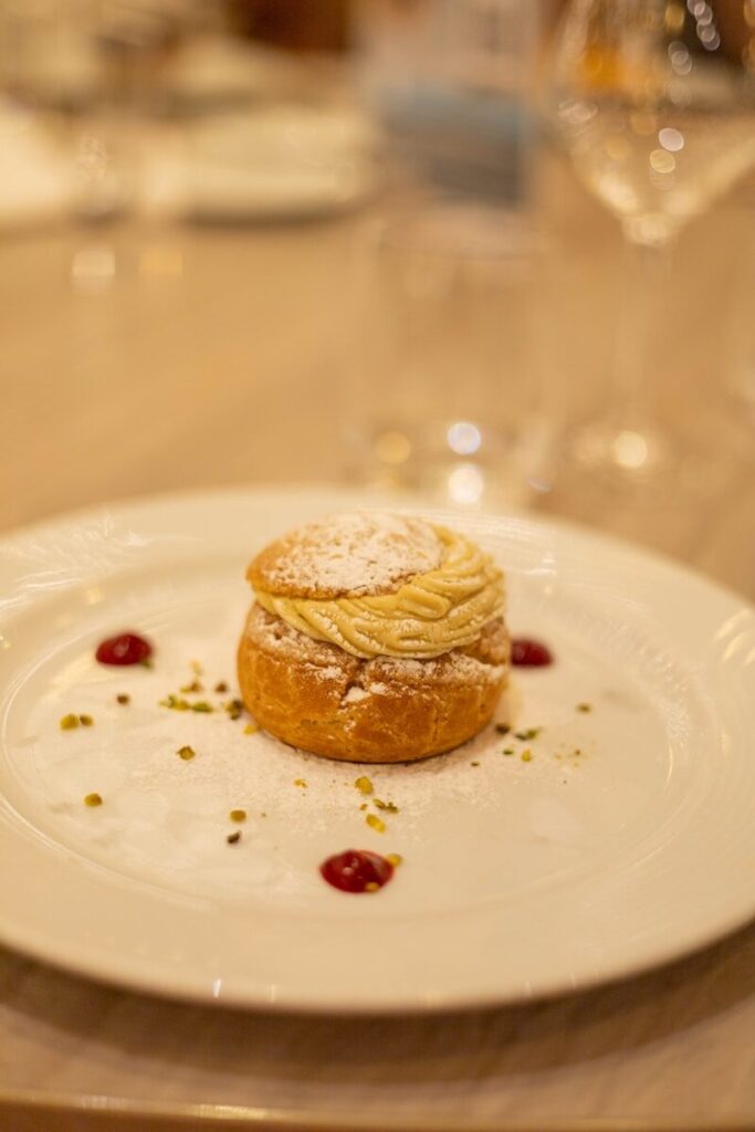 Cream puff dessert with powdered sugar and berry sauce